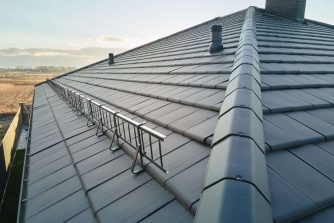 Closeup of house roof top covered with ceramic shingles. Tiled covering of building