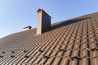 Closeup snow guard for safety in winter on house roof top covered with steel shingles. Tiled covering of building